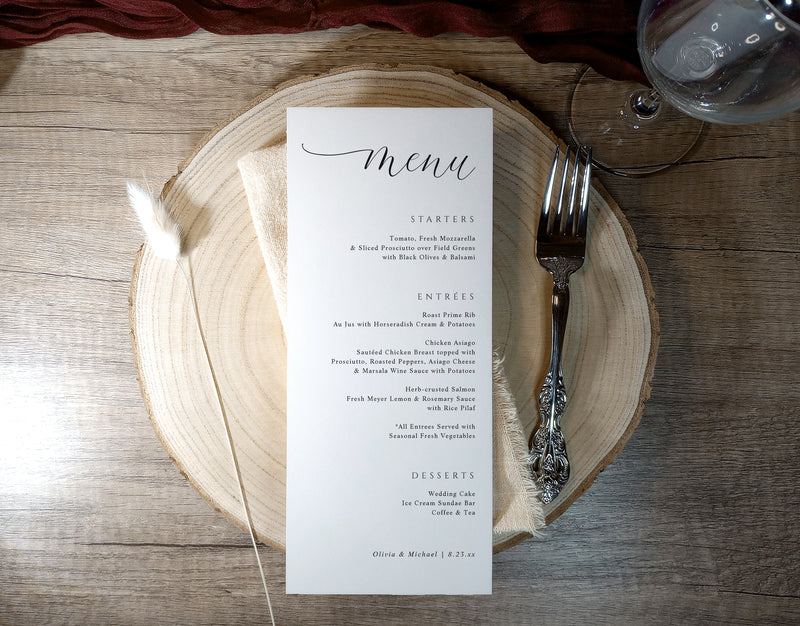 Tall calligraphy menu card personalized with names and wedding date, styled on a table.