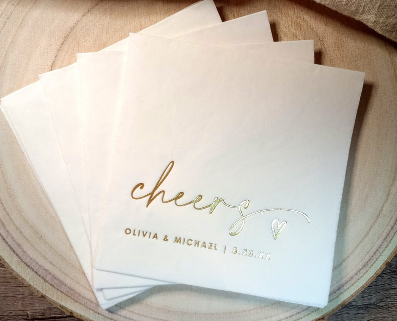 Modern gold “cheers” wedding napkins with heart detail, elegant personalized design