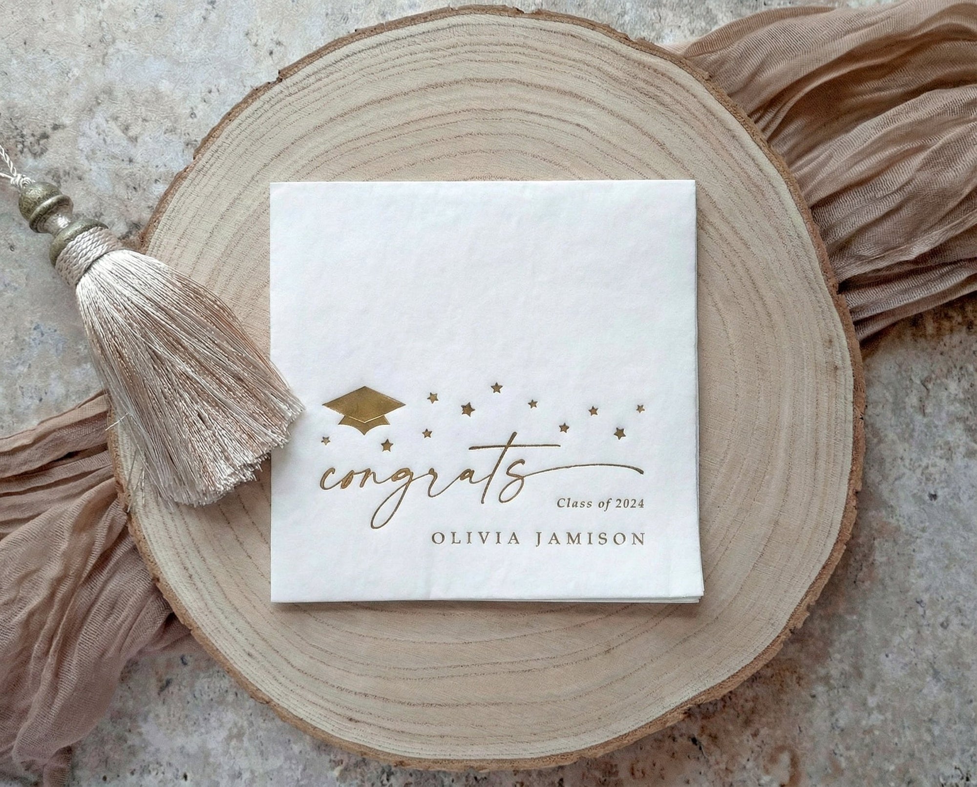 Gold foil graduation napkins with congrats script, stars and graduation cap