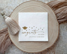 Gold foil graduation napkins with congrats script, stars and graduation cap
