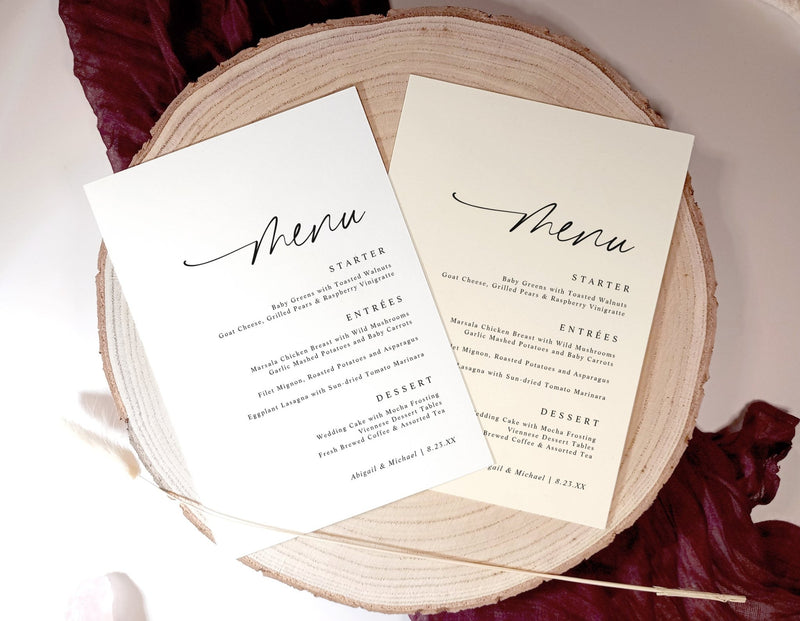 Two wedding menu cards on a wooden round board with a red fabric background