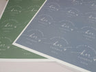 Two sheets of stickers in dusty blue and sage with 'her favorite' text on a white background