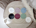 assorted his and her wedding favor stickers in various colors displayed on wood round
