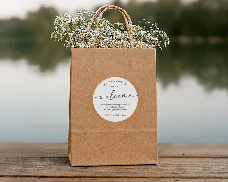 Brown paper bag with flowers and a 'welcome' label on a wooden surface with a blurred natural background