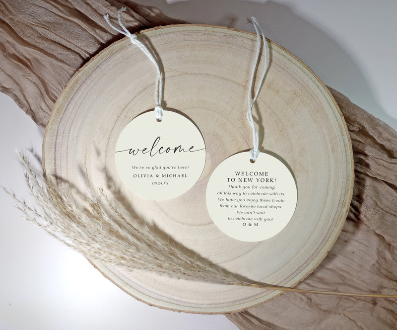 Two round welcome tags hanging from a wooden surface with twine.