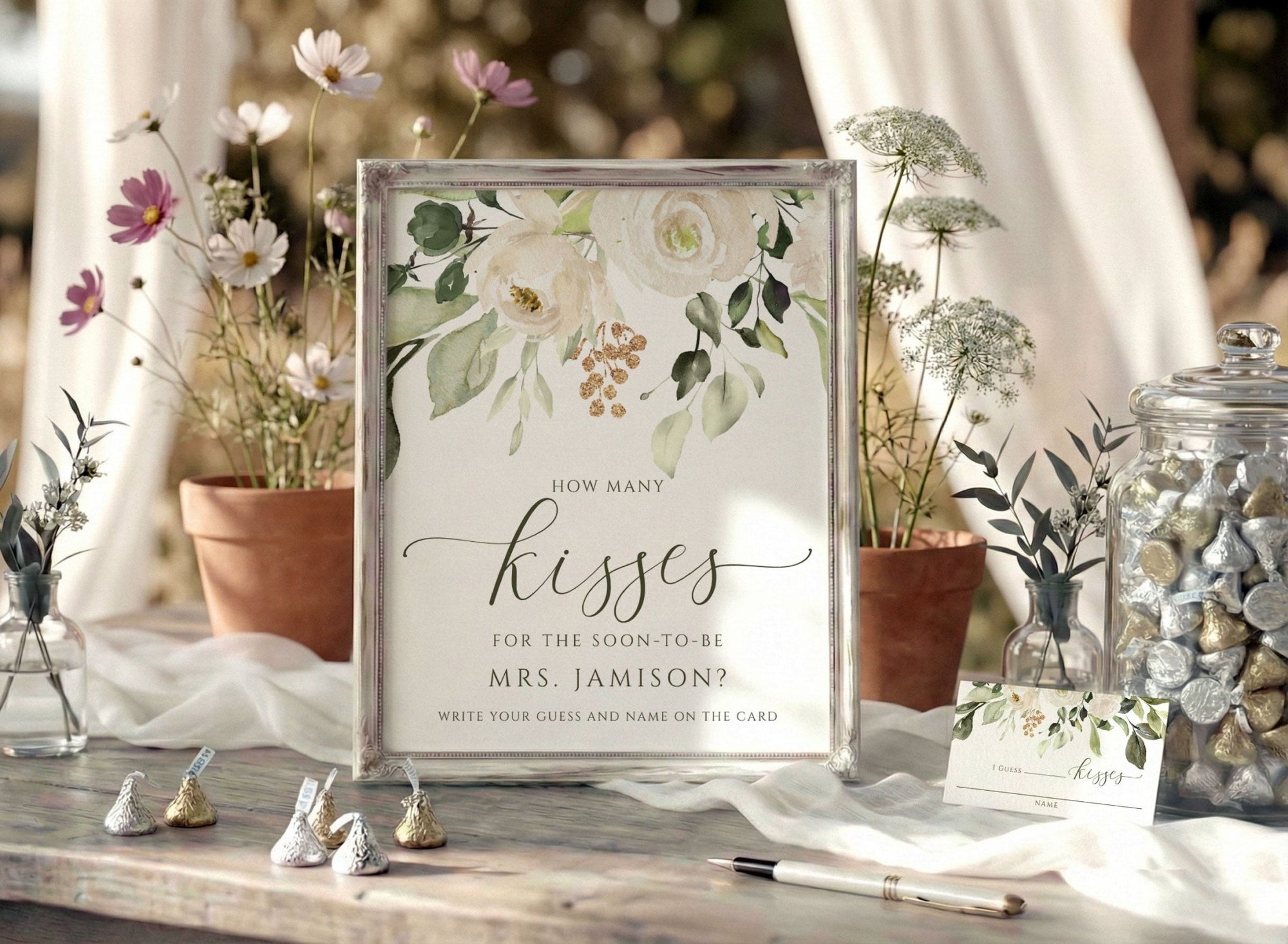 Decorative bridal shower table setting with a floral sign asking 'How many kisses for the soon-to-be Mrs. Jamison?'