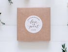 Kraft paper box with a 'Love is Sweet' sticker on a white wooden surface