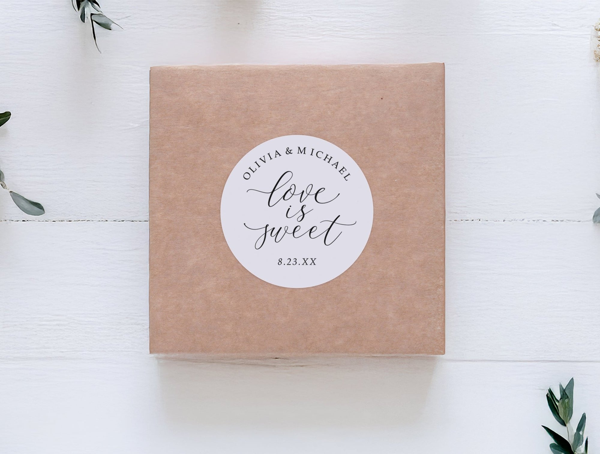 Kraft paper box with a 'Love is Sweet' sticker on a white wooden surface