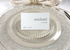 Personalized seating card on glass plate with name and table number in modern typeface