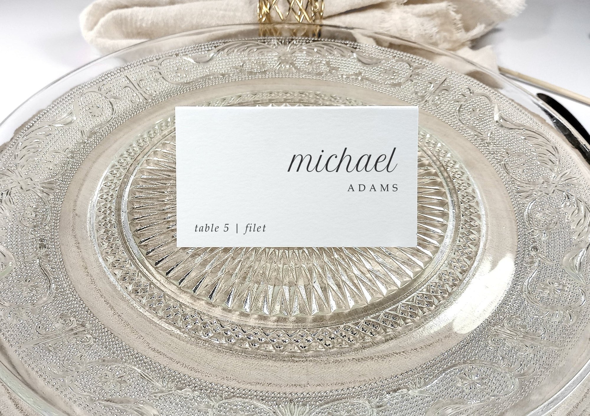 Personalized seating card on glass plate with name and table number in modern typeface