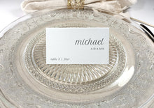 Personalized seating card on glass plate with name and table number in modern typeface