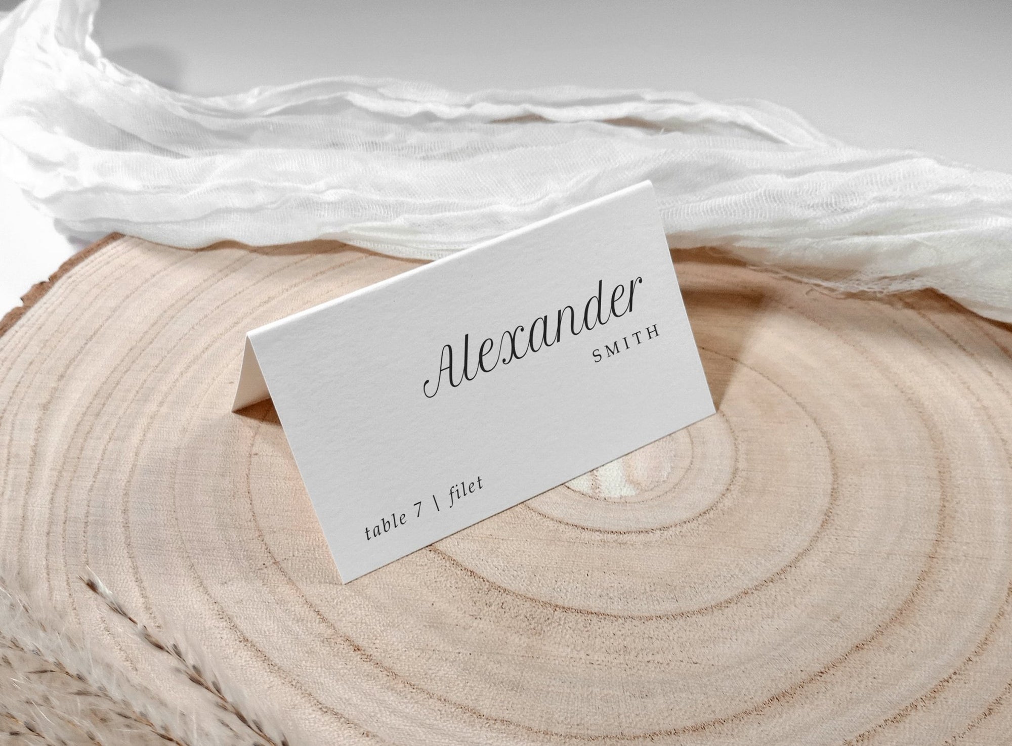 Tented name card with clean black text, styled on wood with sheer fabric