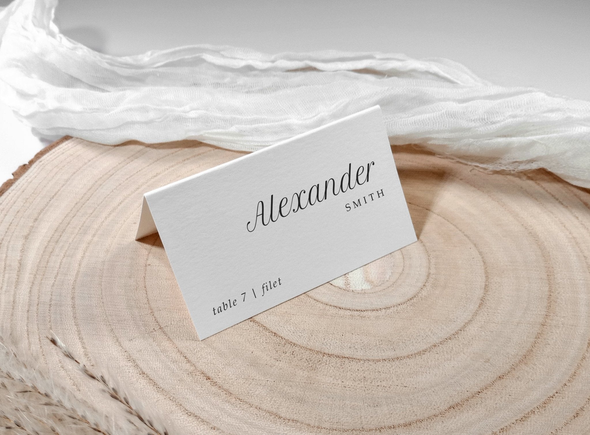 Tented name card with clean black text, styled on wood with sheer fabric