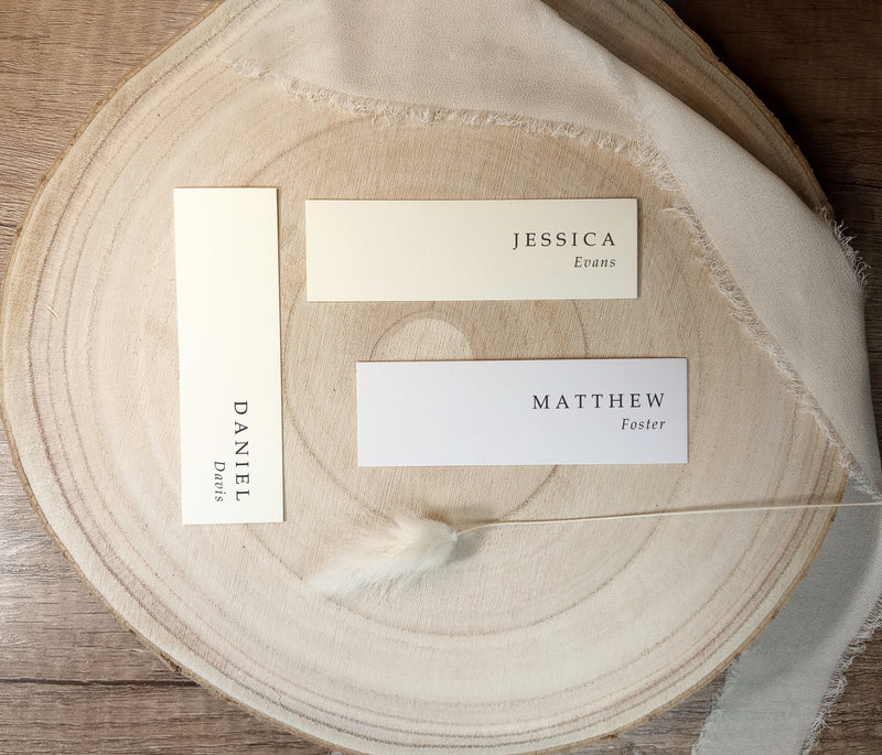 Modern slim name tags printed on cardstock in two sizes, displayed with ribbon on a light wood surface.