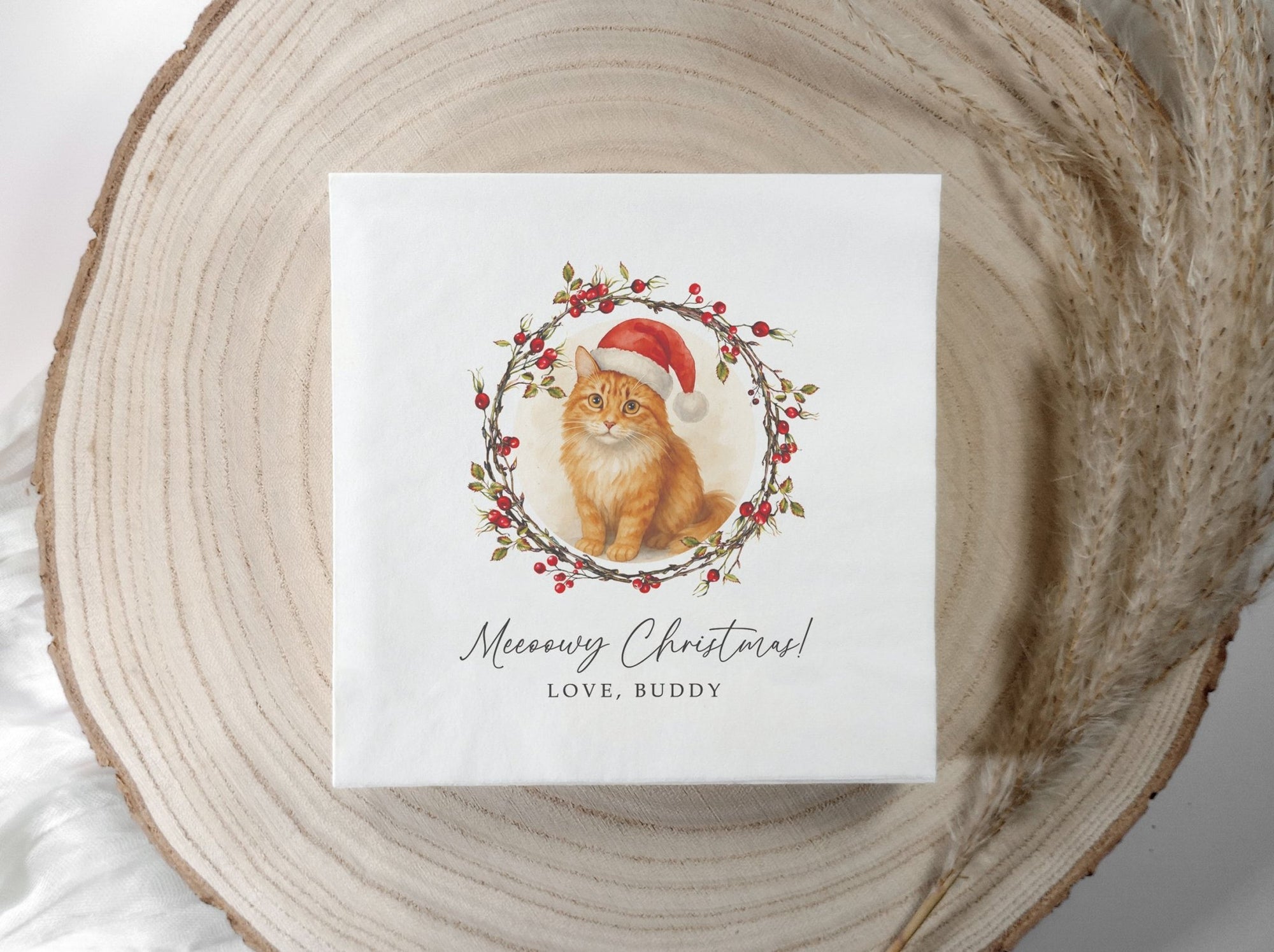 Christmas napkins with an orange tabby cat watercolor portrait wearing a red Santa hat inside a winter greenery wreath on a personalized pet holiday cocktail napkin