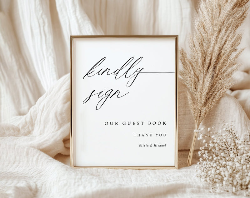 Framed guest book sign with decorative elements on a soft fabric background