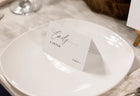 Custom printed place card with romantic script design, resting on a round plate with soft lighting.