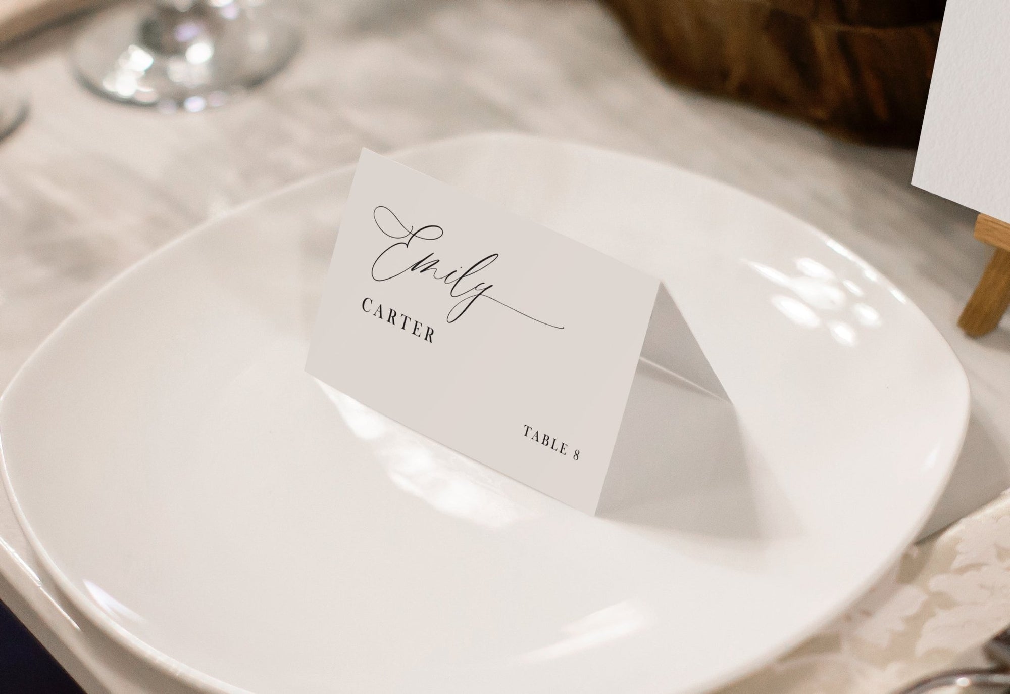 Custom printed place card with romantic script design, resting on a round plate with soft lighting.