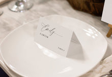 Custom printed place card with romantic script design, resting on a round plate with soft lighting.