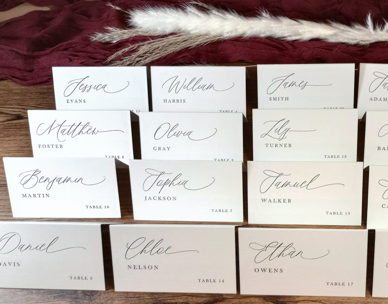 Set of personalized wedding place cards with elegant script, arranged alphabetically for a seating table display.