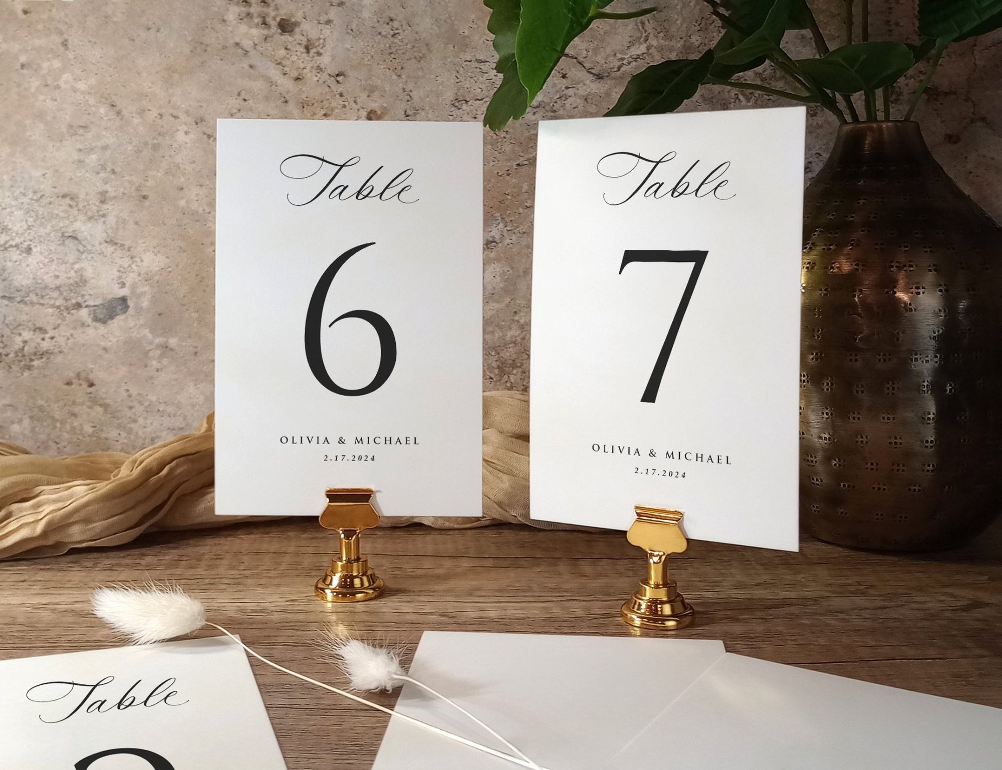 Classic printed wedding table numbers 6 and 7 with names and date, displayed in gold holders.