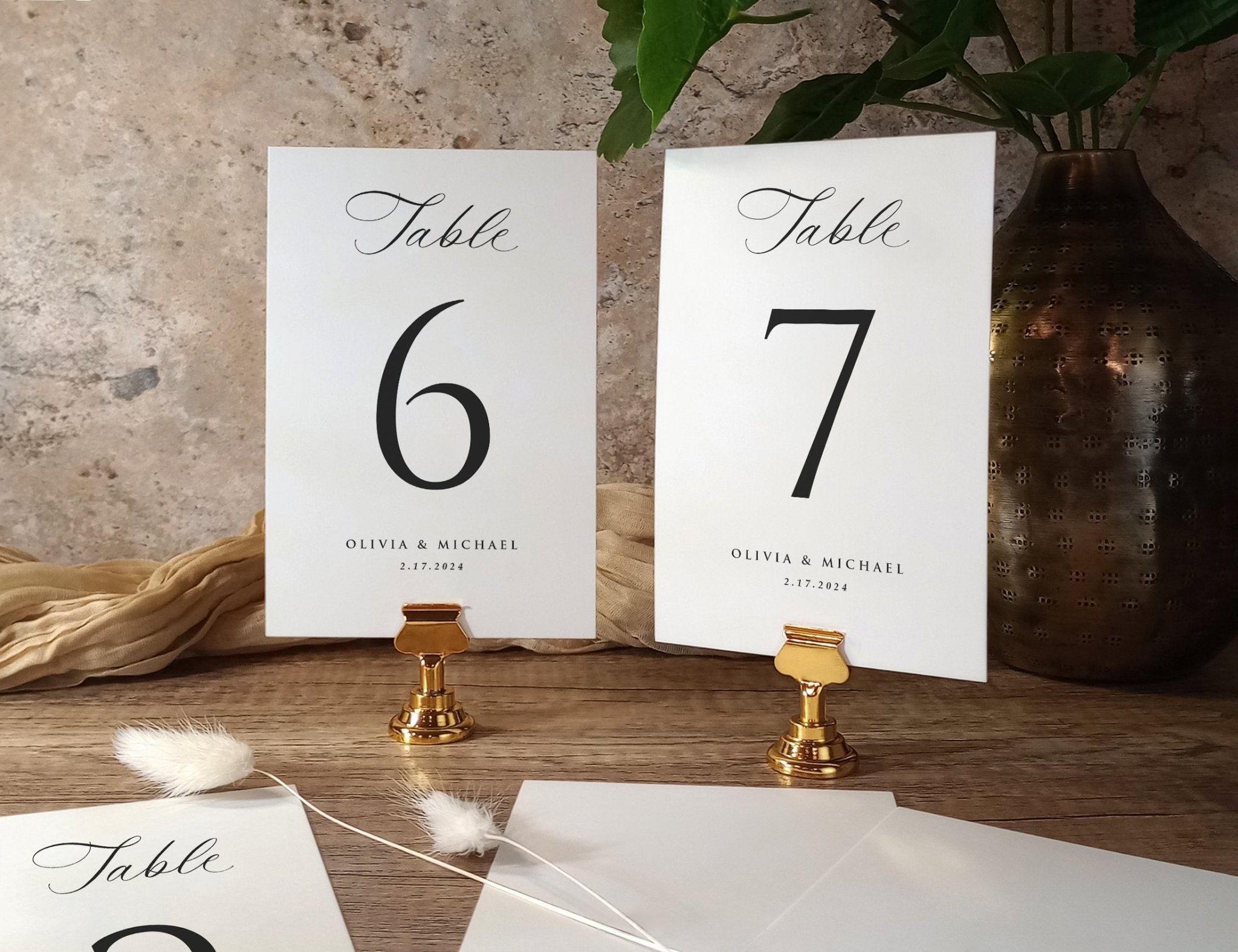 Classic printed wedding table numbers 6 and 7 with names and date, displayed in gold holders.
