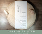 Personalized wedding menu with bottom-aligned text, paired with slim name tag, styled on natural wood charger. Elegant and modern table setting.