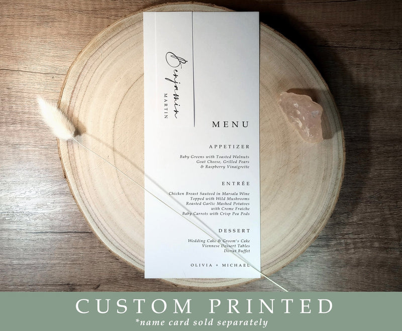 Personalized wedding menu with bottom-aligned text, paired with slim name tag, styled on natural wood charger. Elegant and modern table setting.