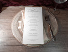 Elegant wedding menu card on a glass plate with silverware on a wooden table