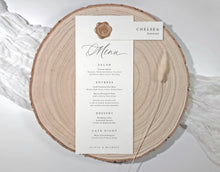 Menu card on a wooden slice with wax seal and name tag.