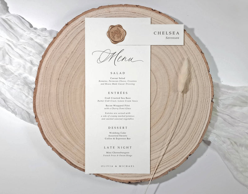 Menu card on a wooden slice with wax seal and name tag.