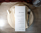 Menu card on a wooden plate with cutlery on a rustic wooden table