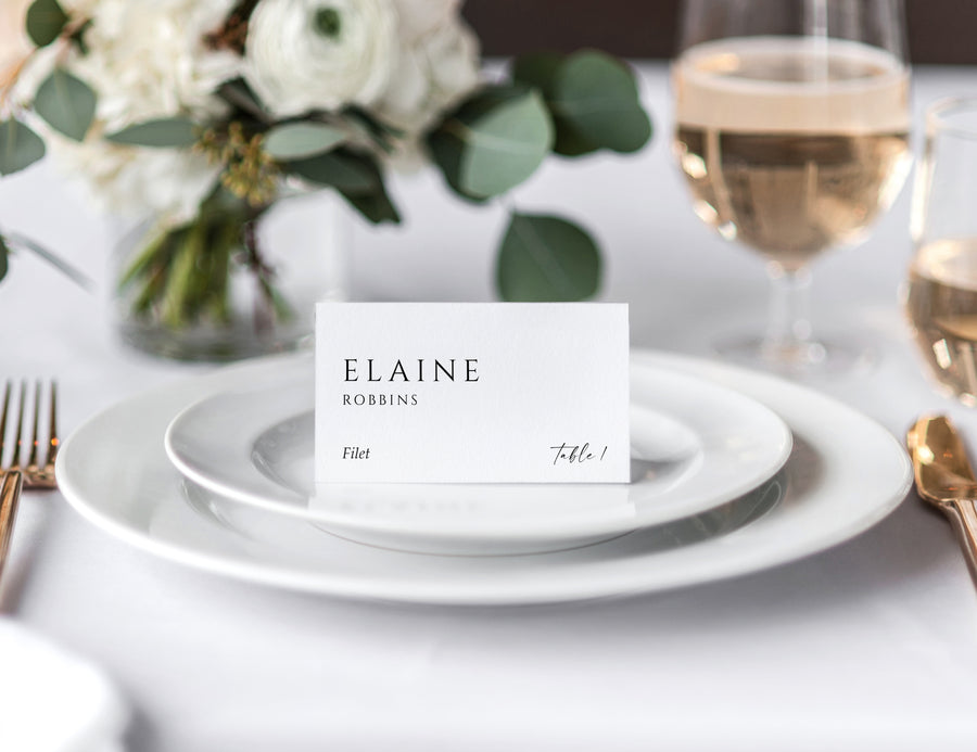 Minimalist wedding tent place card on white plate with guest name, table number, and meal choice