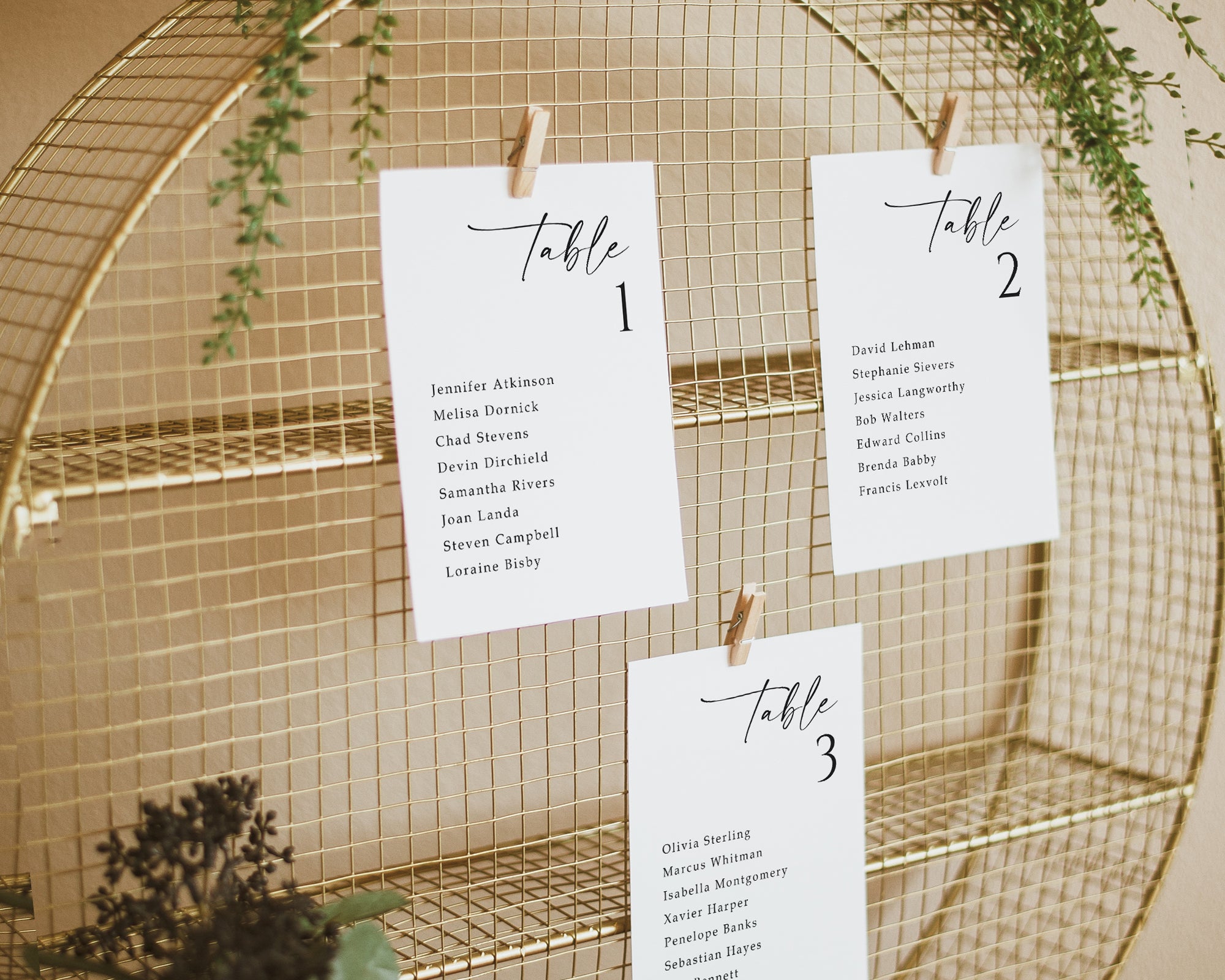 Printed wedding seating cards displayed by table on a gold mesh grid with modern minimalist design.
