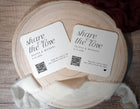 Two coasters with 'share the love' text and QR codes on a wooden surface.