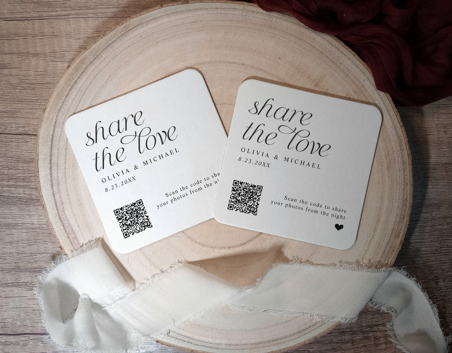 Two coasters with 'share the love' text and QR codes on a wooden surface.