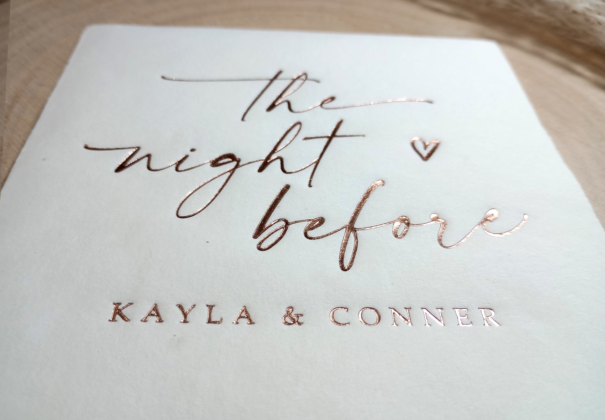 Rose gold foil-stamped rehearsal dinner napkin with ‘The Night Before’ and custom names for a wedding celebration.