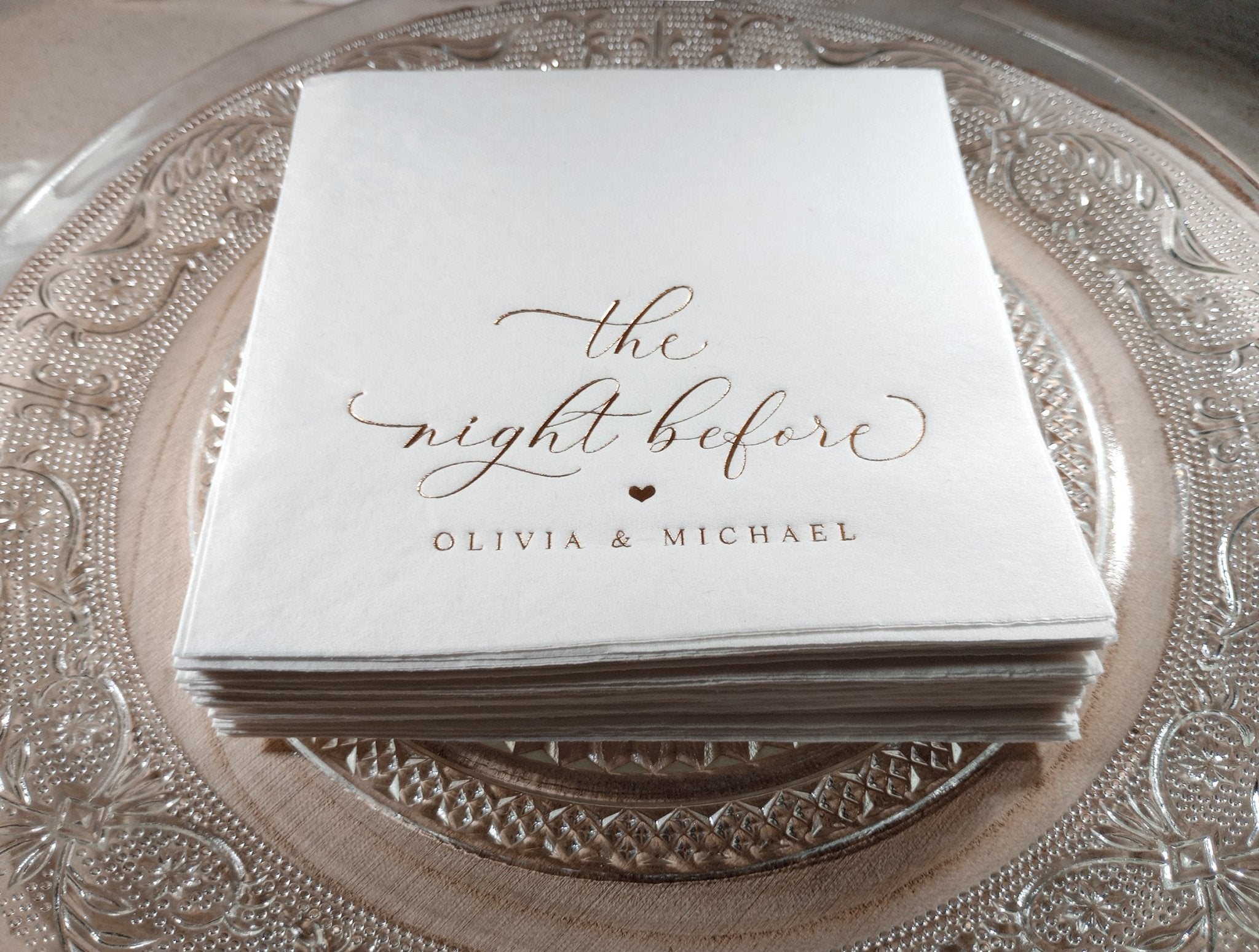 Stack of napkins with 'the night before' and names printed on a decorative plate.