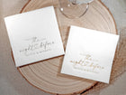 wo stacks of white napkins—one with gold foil and one with silver foil—both featuring “the night before” script with a heart and names.