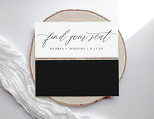 Wedding seating card with 'find your seat' text on a wooden slice and white fabric background