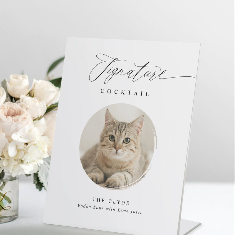 Wedding signature drink sign with cat photo on self-standing pedestal next to white roses