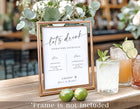 Signature drinks wedding sign in elegant handwriting displayed in a gold frame with cocktails beside it