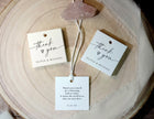 Three 'thank you' tags on a wooden surface with a decorative stone.