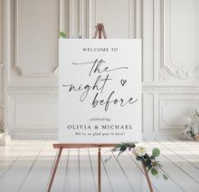 Rehearsal dinner welcome sign on an easel with floral arrangement in a room with white walls and wooden floor.