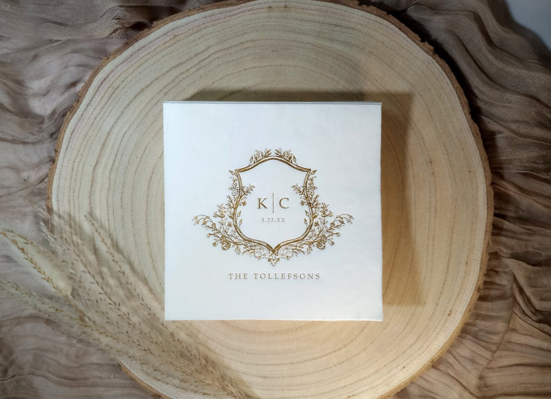 foil stamped vintage crest wedding napkin with couple's initials and names on wood charger