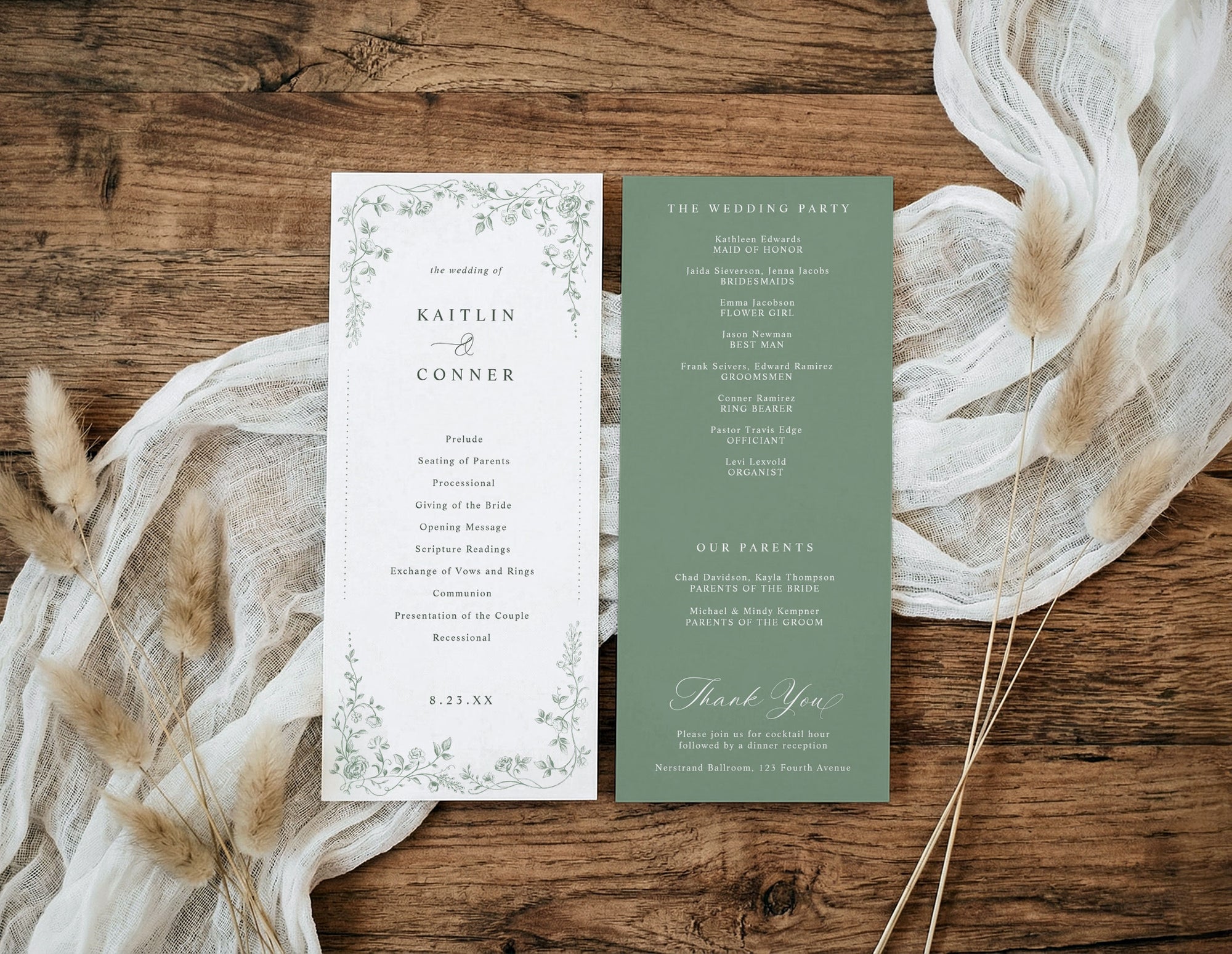 A flat-lay of a double-sided wedding program or invitation set on a rustic wooden surface, styled with cream gauze and dried pampas grass. The left page is white with delicate green floral borders and black text, and the right page is sage green with white text.
