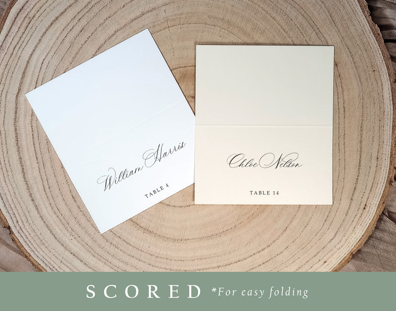 Printed place cards shown in flat and folded (scored) formats on a wood charger, serif font style.