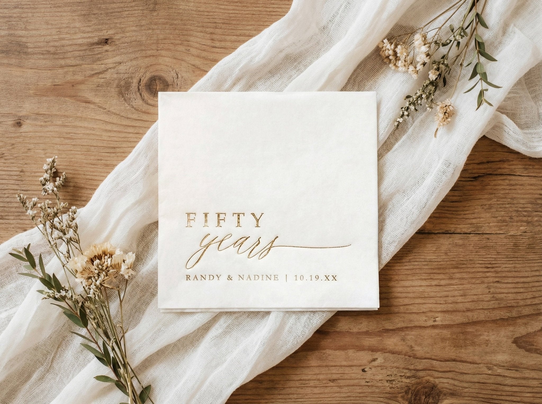 Gold foil 50th anniversary cocktail napkins with elegant script reading fifty years
