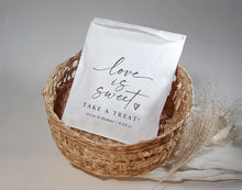 Custom printed wedding favor bag with “Love Is Sweet” script and minimalist heart design in a wicker basket