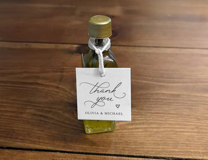 Small olive oil bottle with a gold cap and a 'thank you' favor tag on a wooden surface